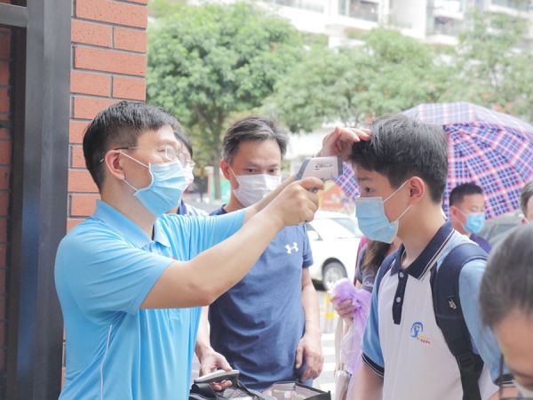 进校门测量体温。 叶京京/摄影