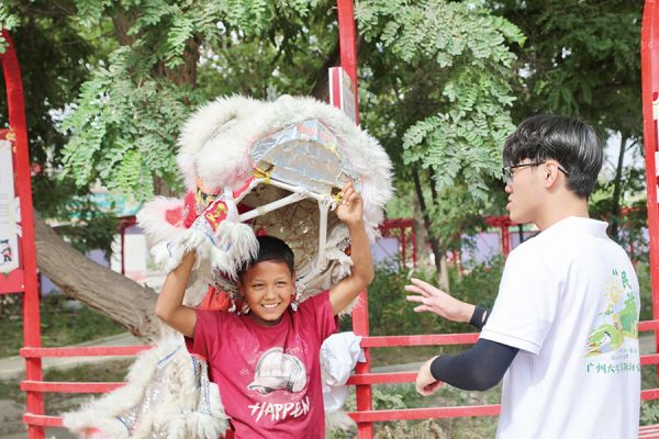 广州大学实践团同学与当地青少年一起体验舞狮文化
