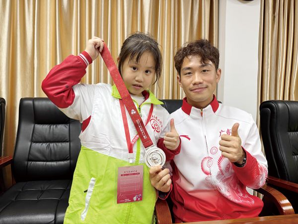 小记者与运动员手持全运奖牌合影留念