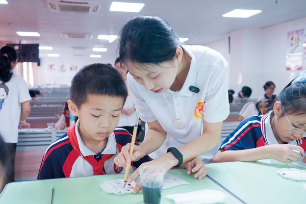 大学生指导小学生创作红军主题通草画作