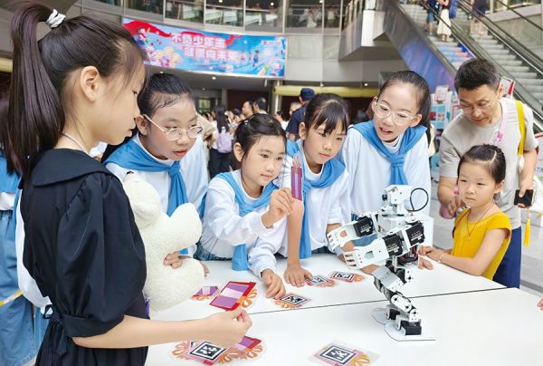 孩子们与市少年宫师生自主编程的机器人互动
