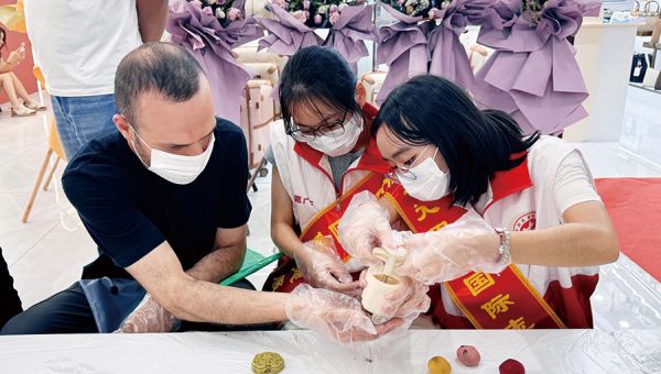 志愿者和采购商、皮具城商户一起制做中秋月饼